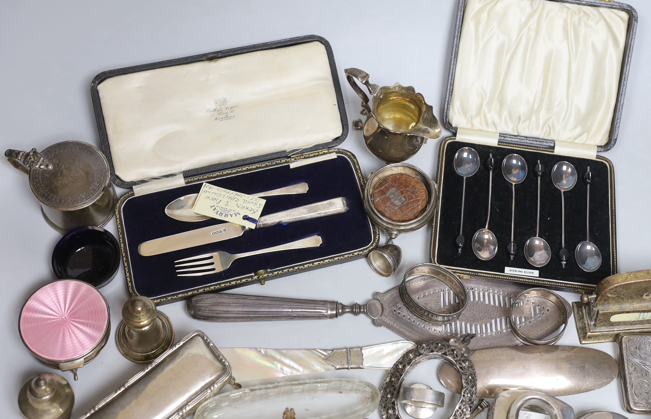 A group of assorted minor silver, including cased coffee spoons, christening trio, Georgian silver cream jug, cigarette case, trinket box, condiments, enamelled box, sugar nips, flatware, George III fish slice, London, 1